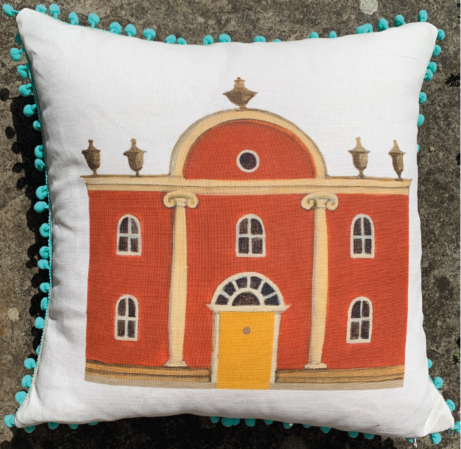 Folly Cushion with blue pom poms